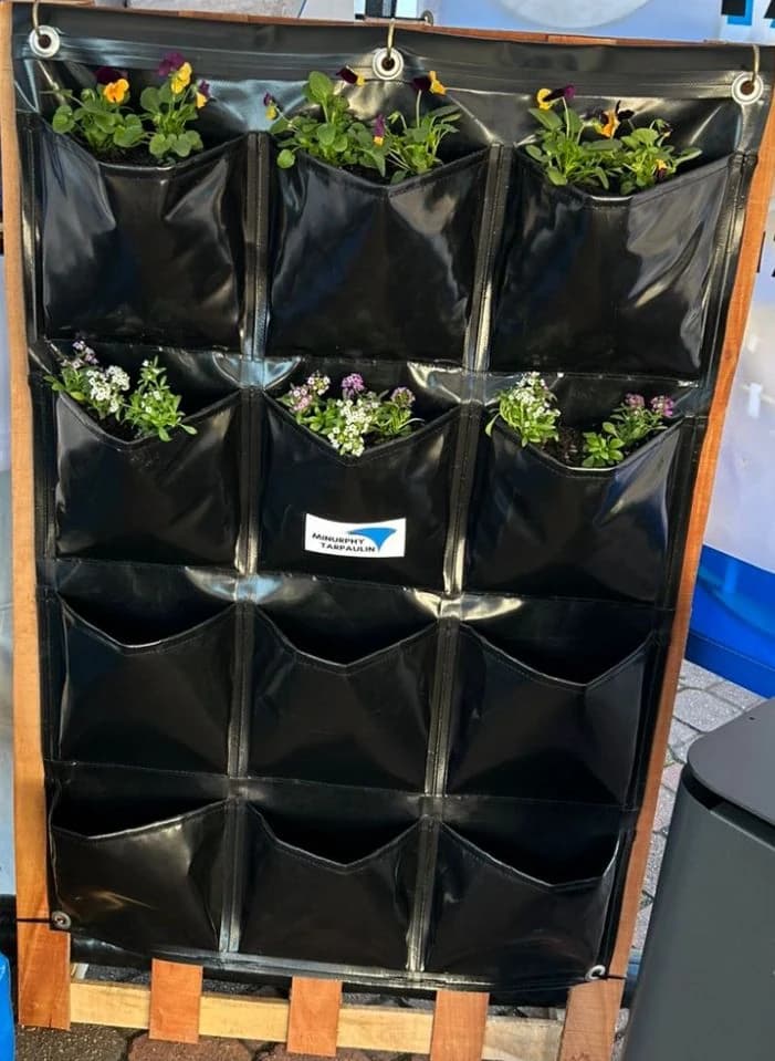 Custom Minurphy vertical hanging planter with twelve PVC pockets filled with flowers and herbs