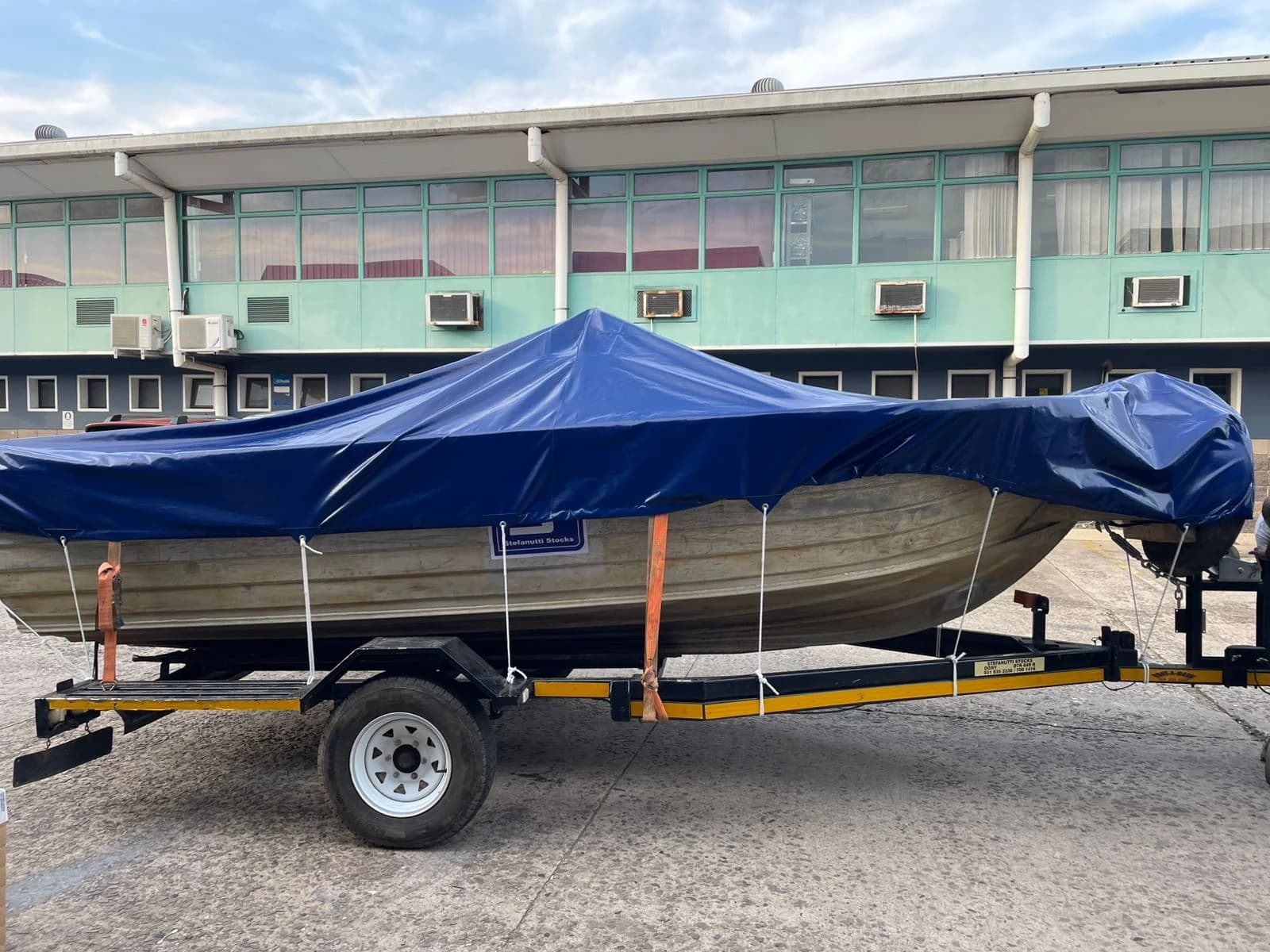 Side view of an aluminium boat under a navy-blue Minurphy boat cover