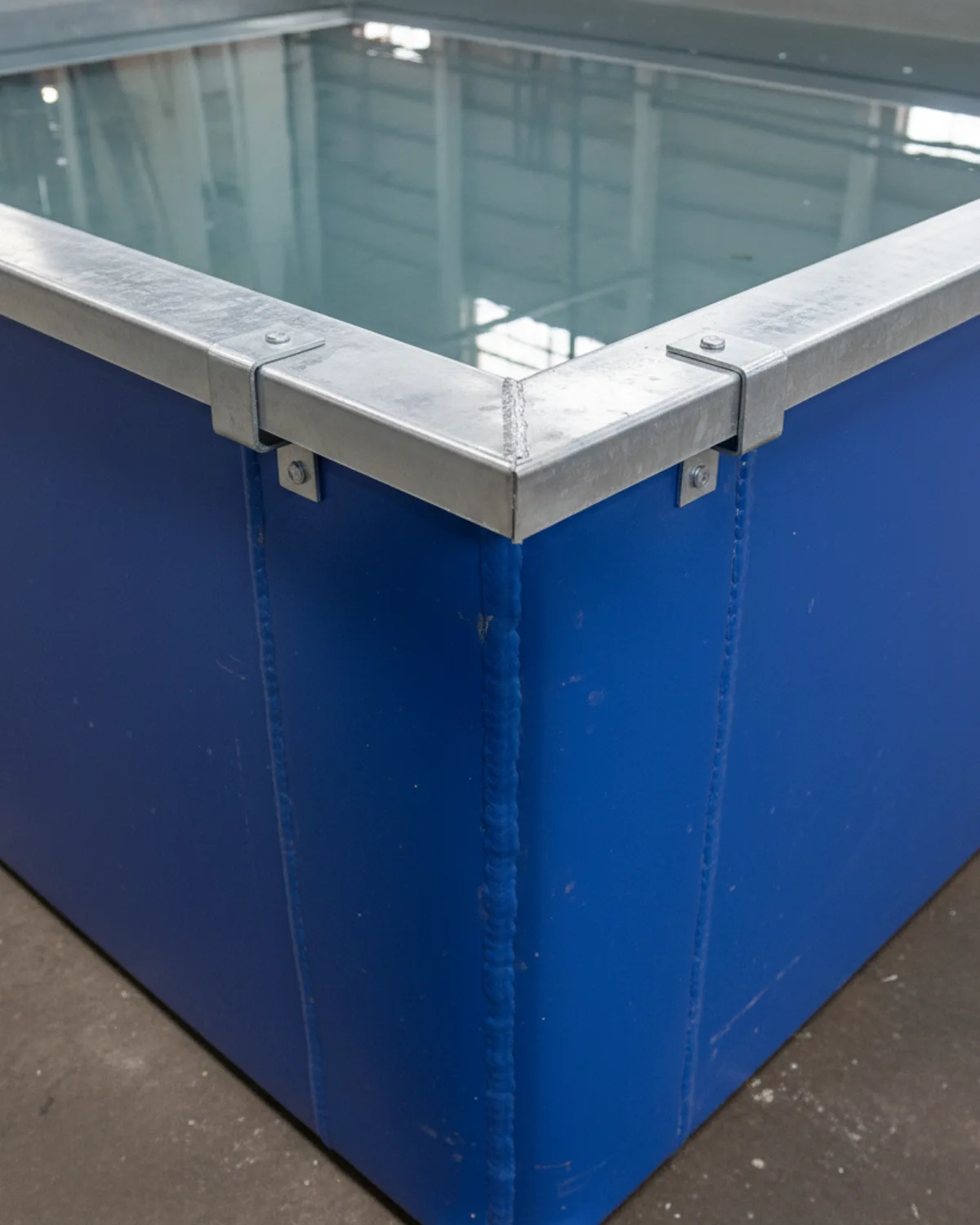 Top corner of a rectangular PVC ice bath showing galvanised steel rim, corner bracket, and RF-welded vertical seam