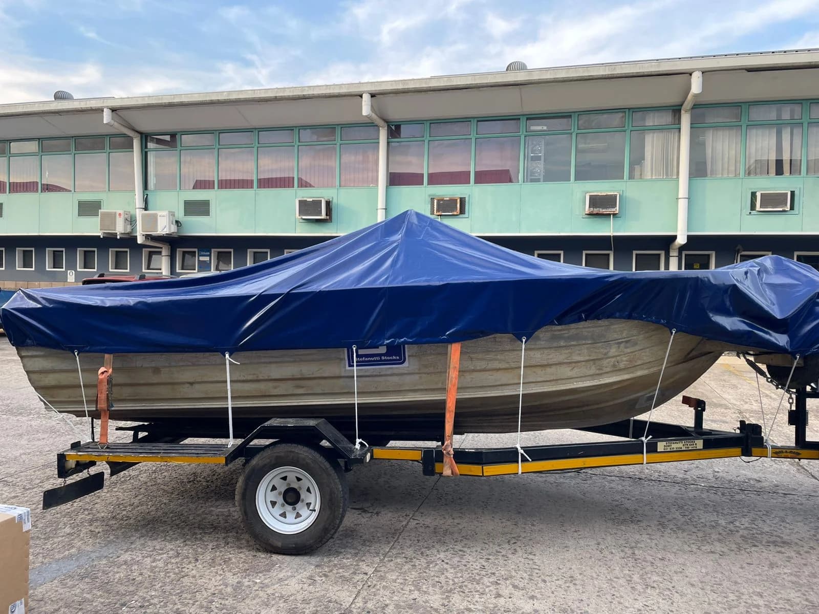 Aluminium boat on a trailer fitted with a Minurphy navy-blue PVC boat cover